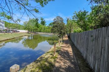 a small pond next to a fence and trees at Reserve of Jackson Apartment Homes, Mississippi, 39211